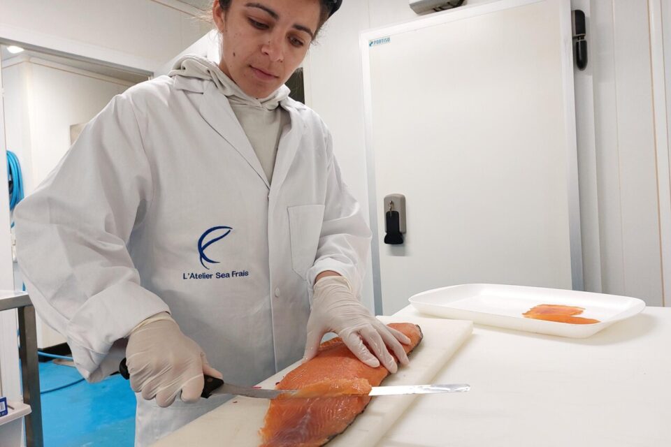 Manon Testi, le chef de l'atelier Seafrais de fumage de poisson de Dragey-Ronthon débite à la main ou au couteau pneumatique les filets de saumon en fines tranches.